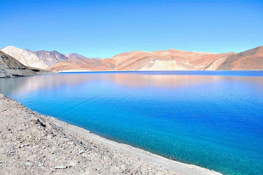 Soak in the beauty of Pangong Lake with its crystal clear blue waters and picturesque mountain backdrop