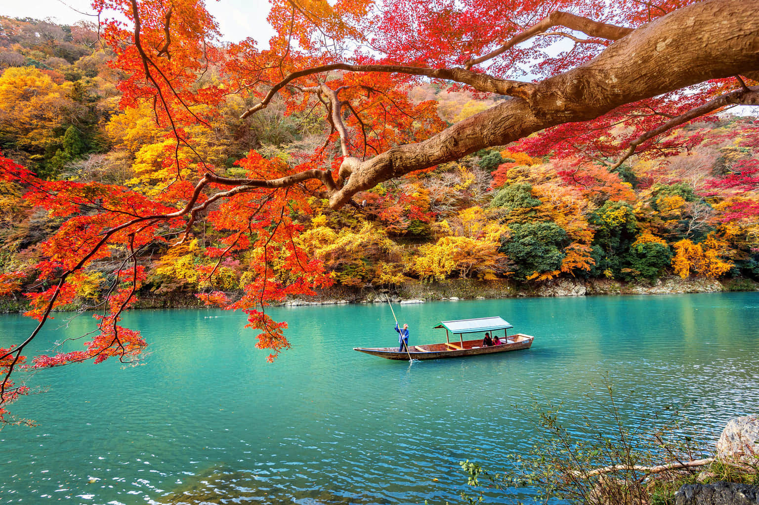  A scenic boat ride on the Hozu River in Arashiyama, Japan, surrounded by vibrant autumn foliage.