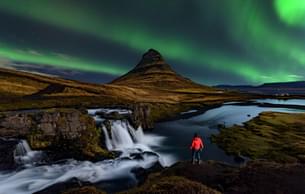 Tourist enjoying the view of Northern lights at Kirkjufell, Iceland