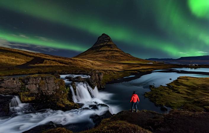 Tourist enjoying the view of Northern lights at Kirkjufell, Iceland
