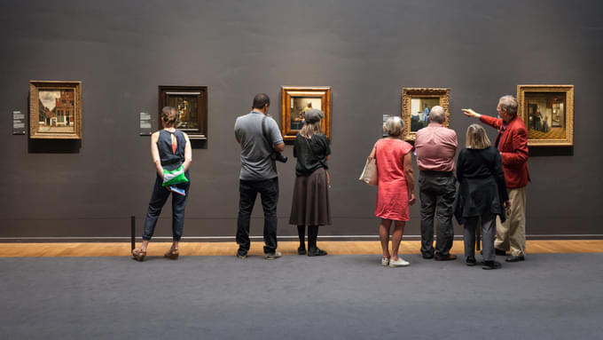 A museum guide explaning tourists about the Paintings in Rijksmuseum