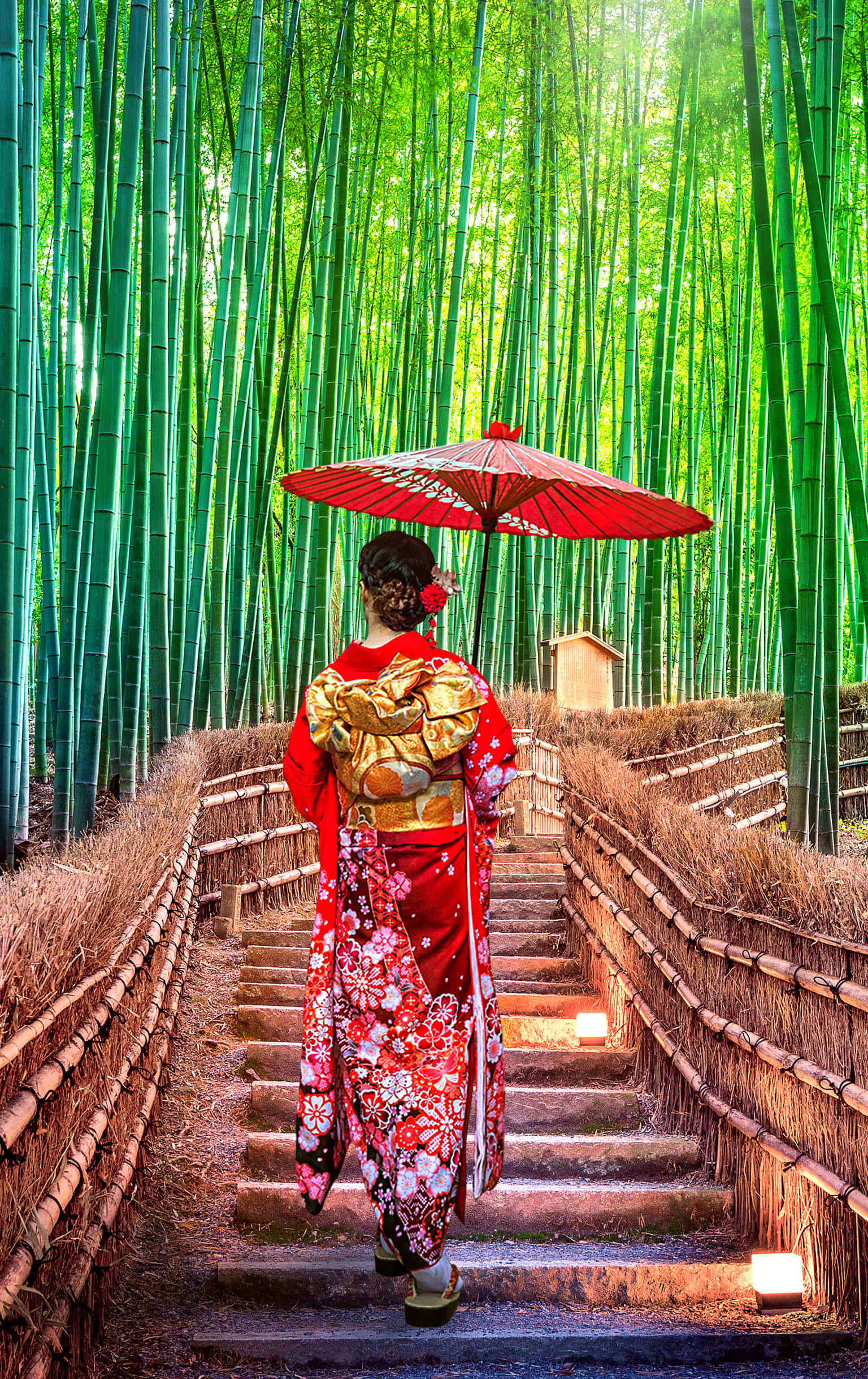 Woman in a red kimono holding a parasol, walking through a bamboo forest.