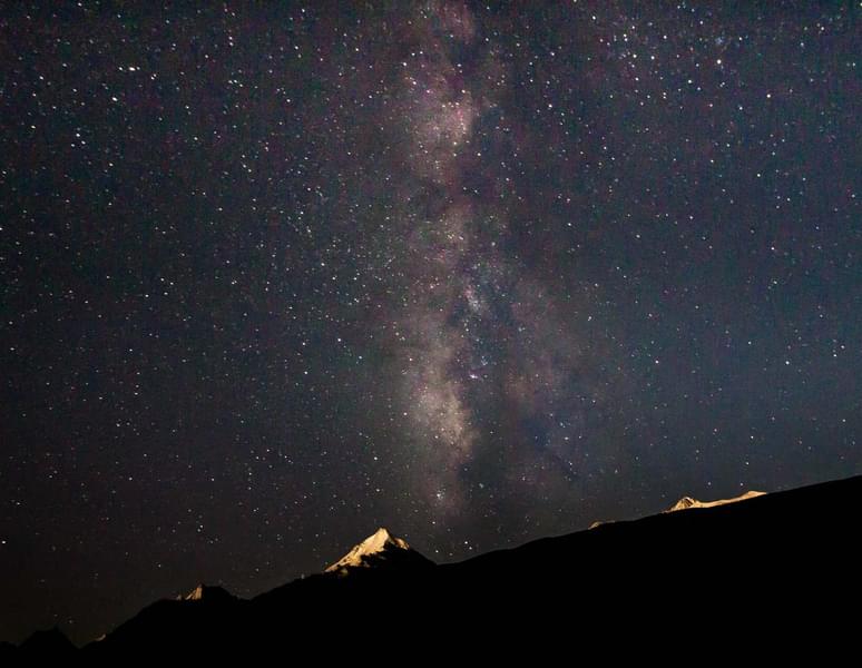 See the magnificent Milky Way stretching across the sky above the Three Sisters Mountains.