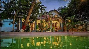 Outdoor view of the homestay with swimming pool and tropical trees 