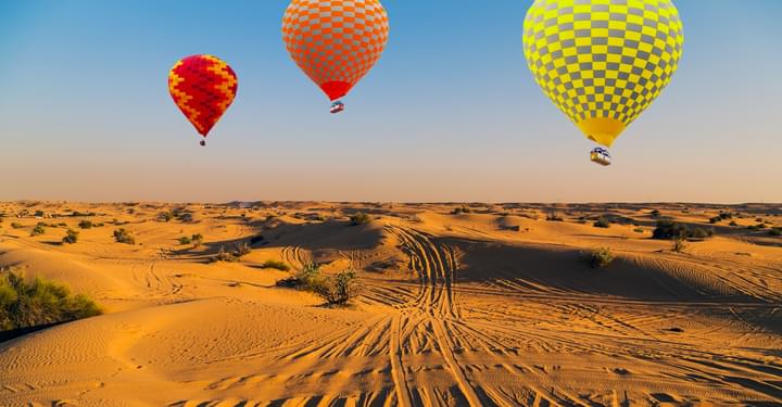 Three hot air balloons fly over the Dubai desert