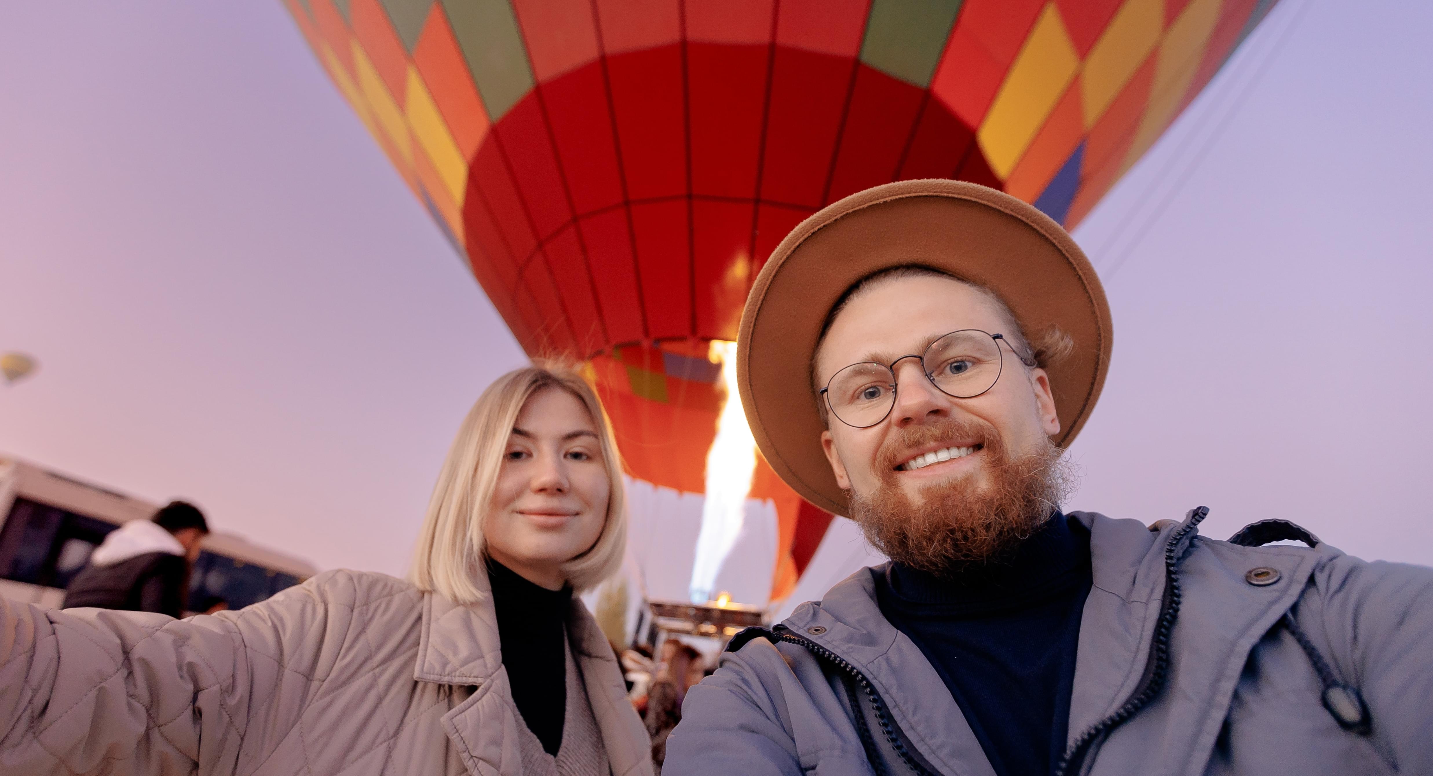 Happy man taking selfie photo on phone with hot air balloons in Dubai