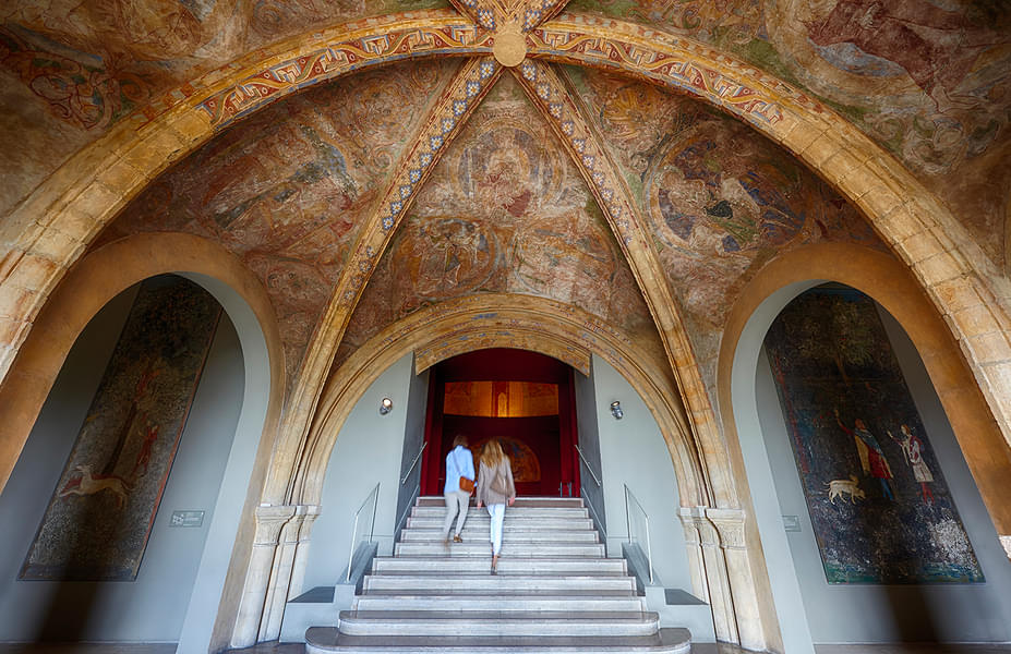 Observe the intricate fresco art across the museum's ceiling