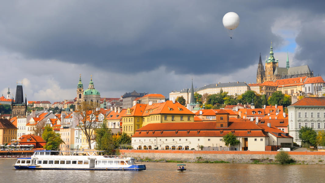 View from Prague Vltava river; early autumn, sunlit old roofs under dramatic skies
