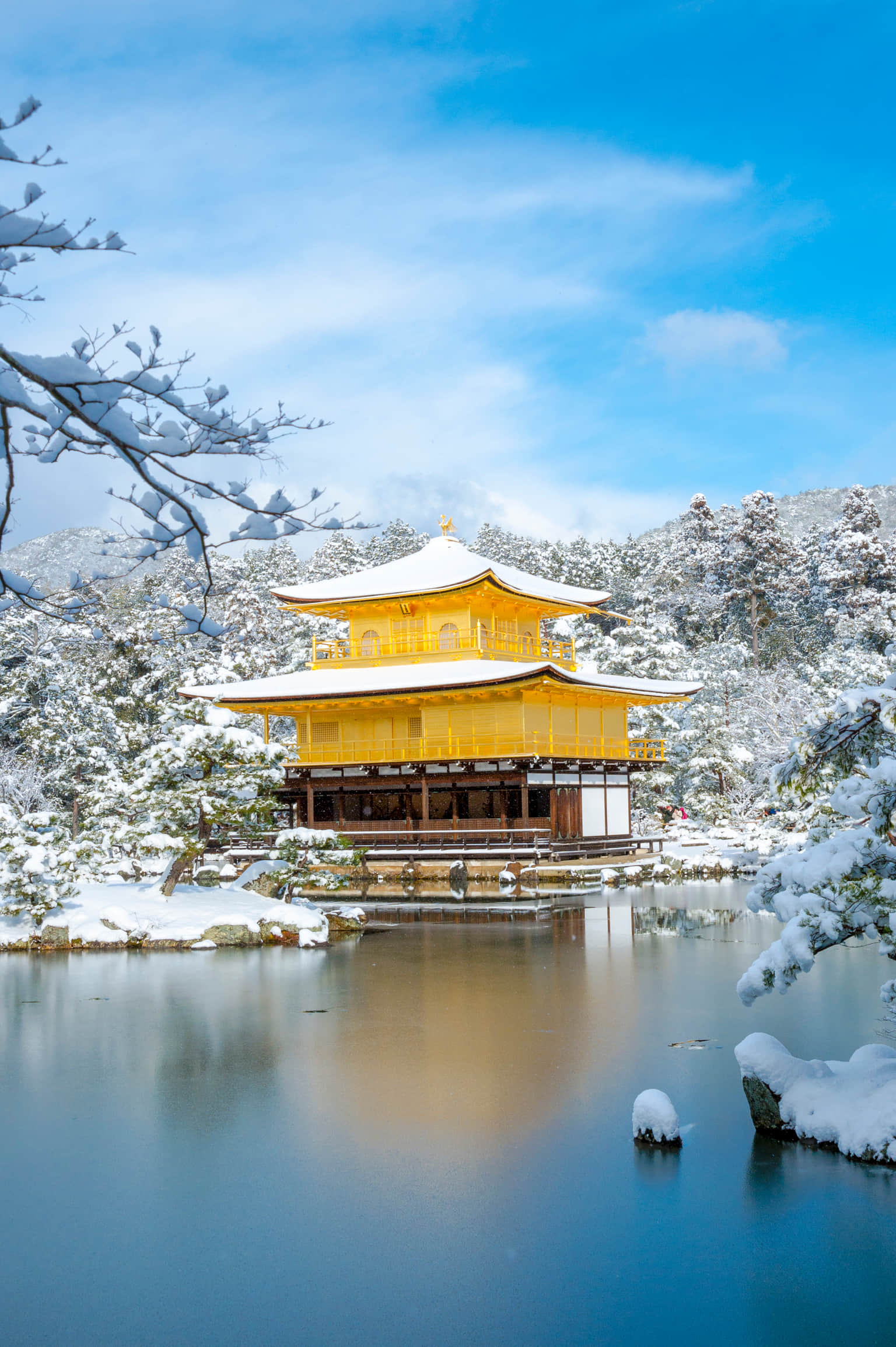 Kinkaku-ji Temple in Kyoto covered in snow, reflecting on the water.