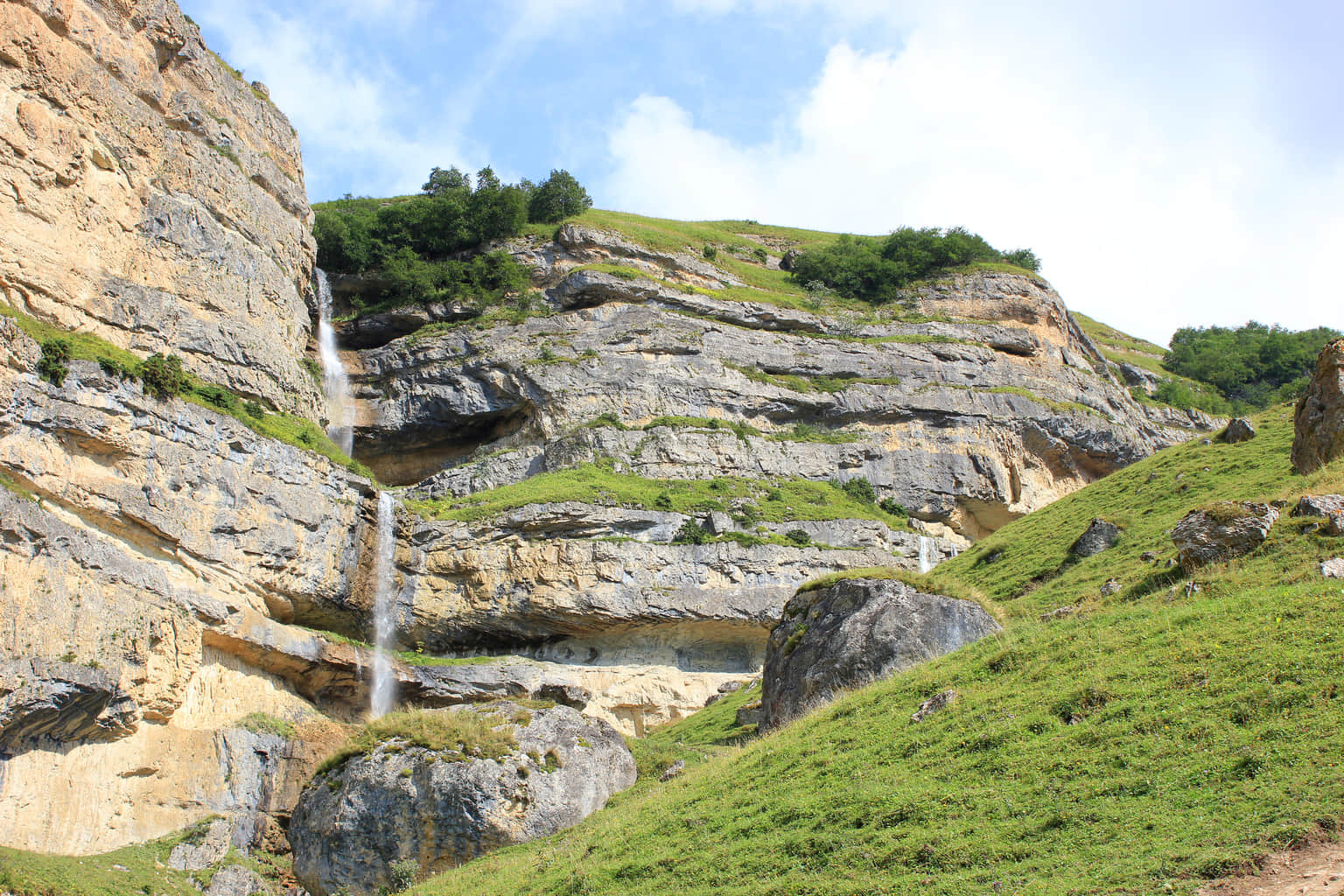 Scenic hillside with a cascading waterfall and rocky cliffs in Azerbaijan.