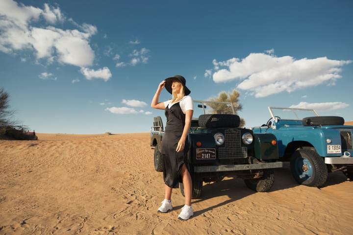 A girl wears white shoes amidst Dubai's desert with jeeps