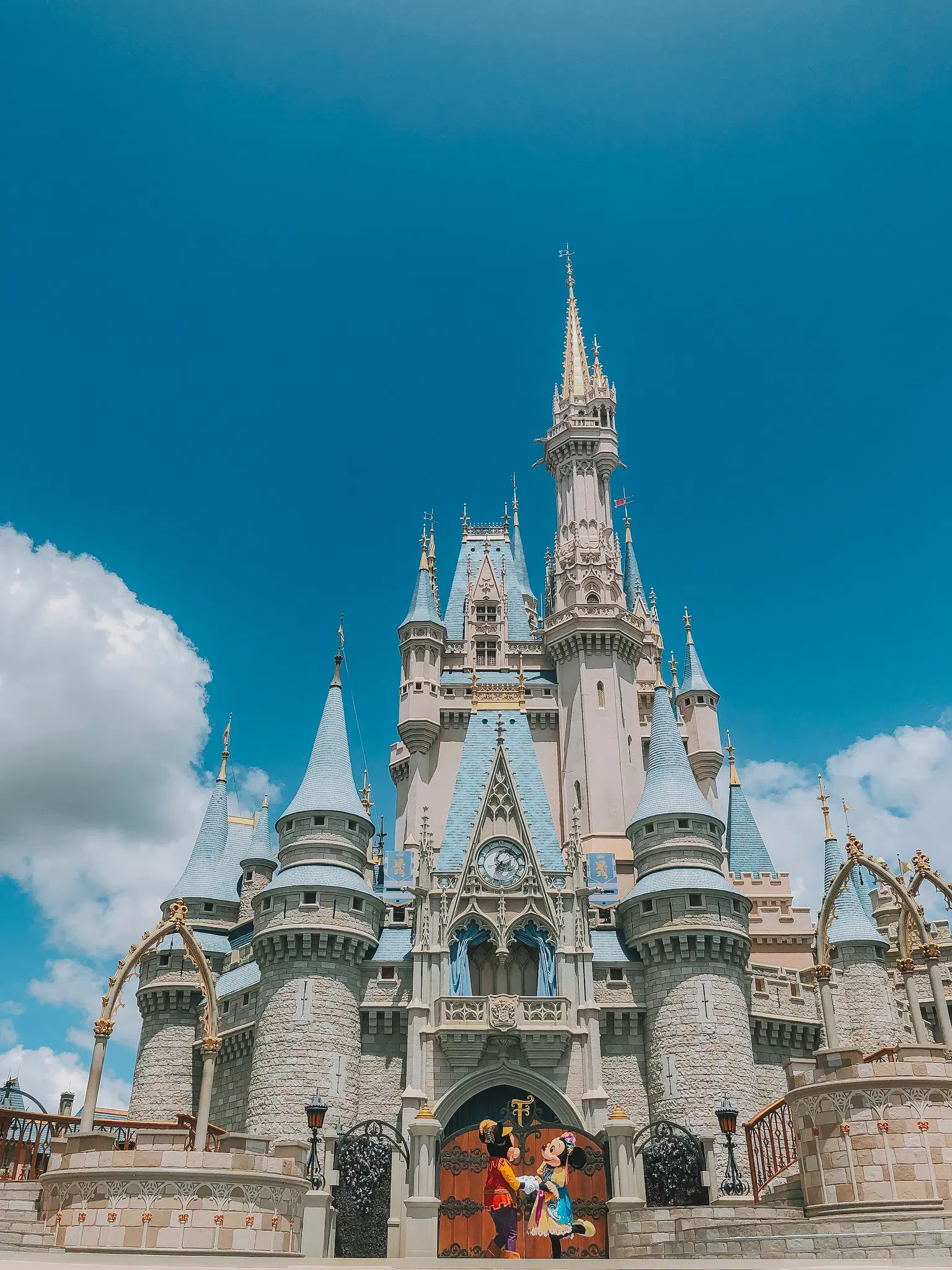 Majestic fairytale castle with towering spires against a bright blue sky.