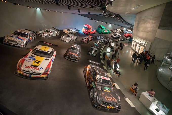 Stand among legendary Mercedes-Benz race cars and trucks in a dramatic motorsport display at Mercedes-Benz Museum