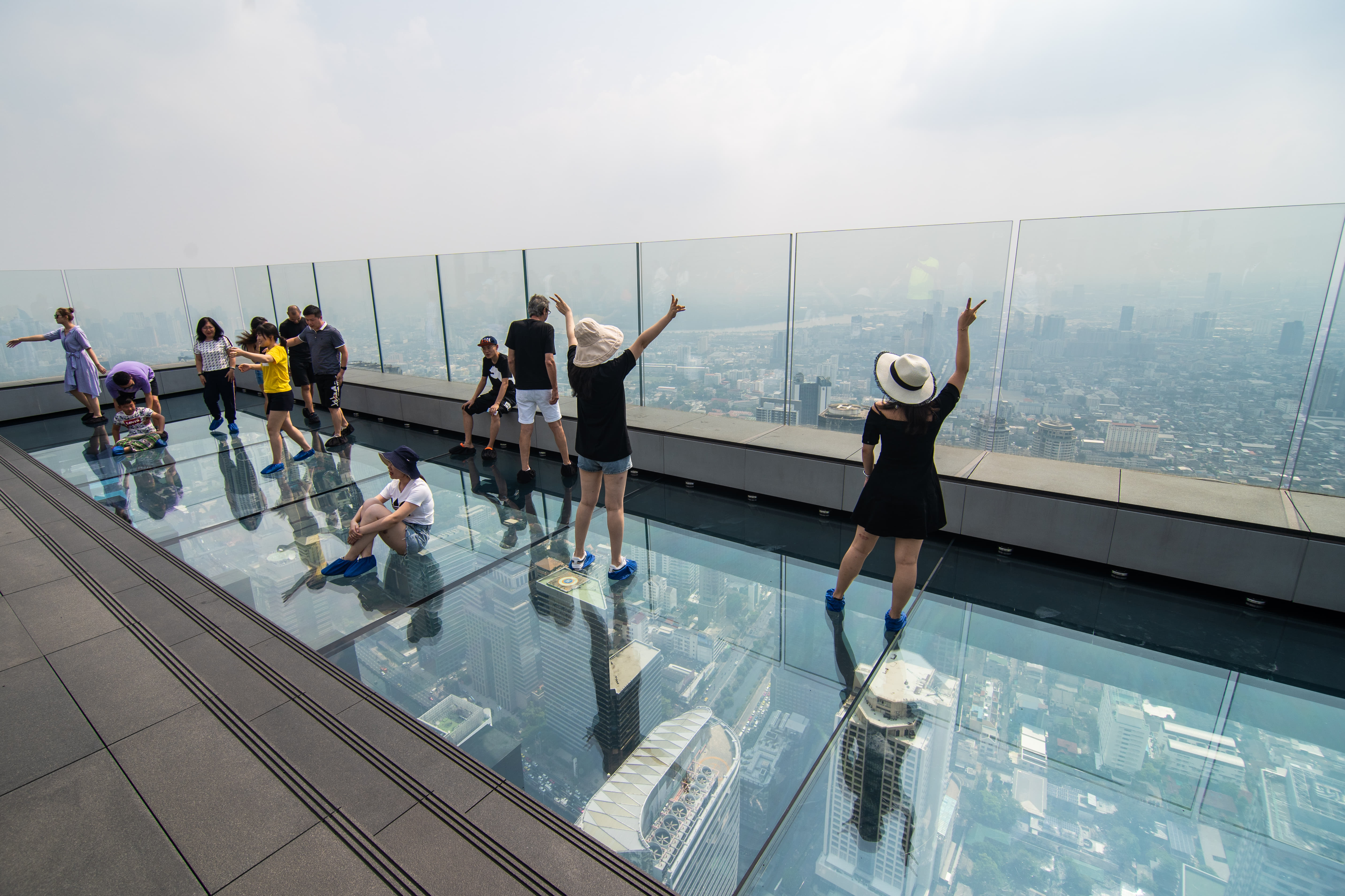 Visitors standing on the glass floor of Mahanakhon SkyWalk above Bangkok
