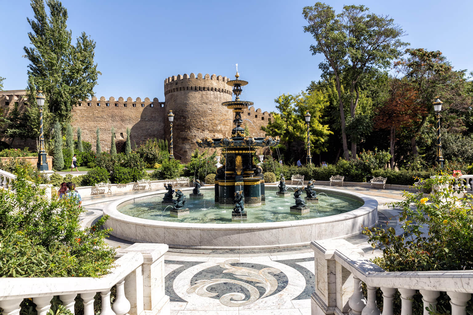Elegant fountain surrounded by greenery near Baku's historic city walls.