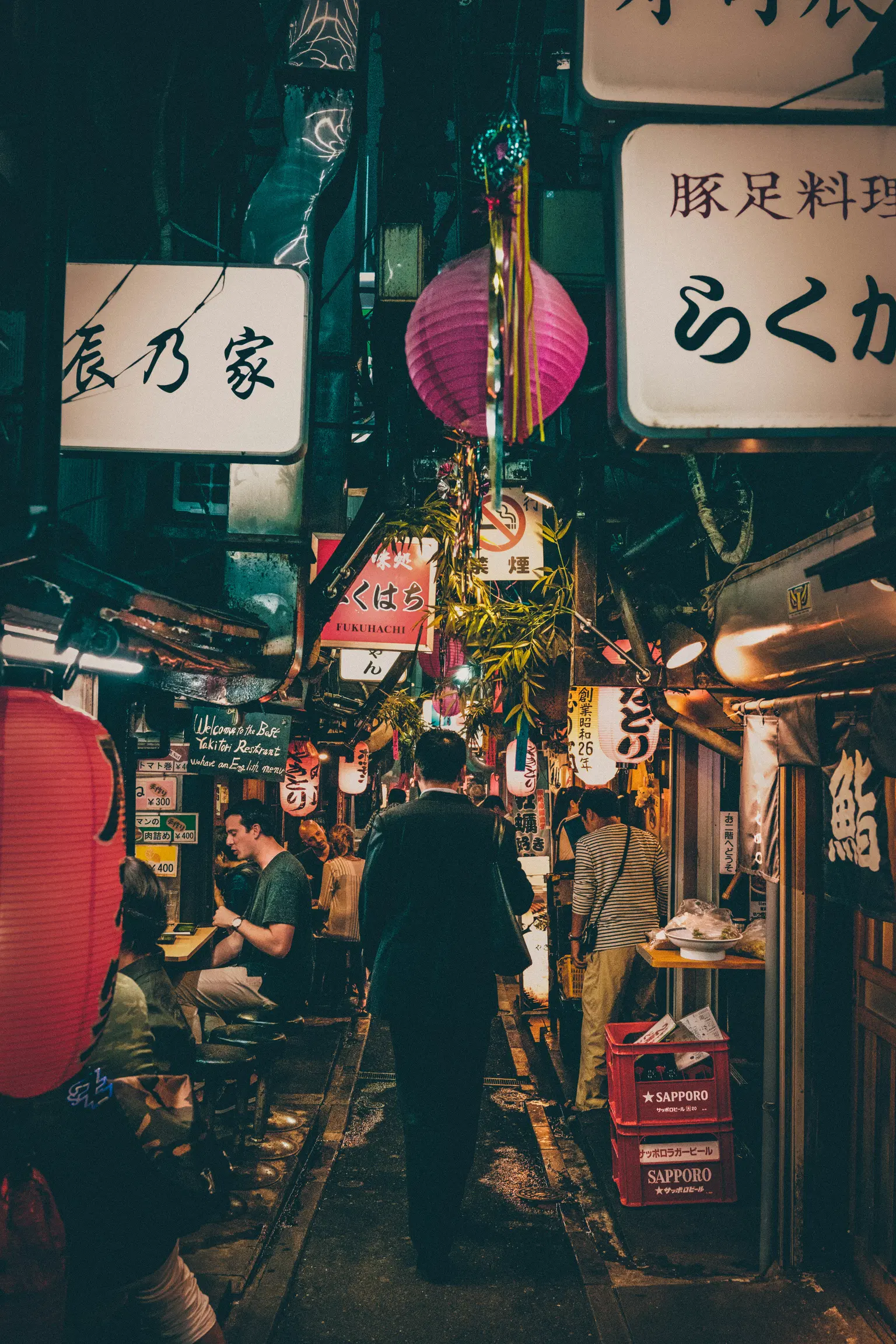 Bustling alleyway with lanterns and street food stalls in Japan.