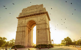 See India Gate at sunrise with birds chirping in the background.