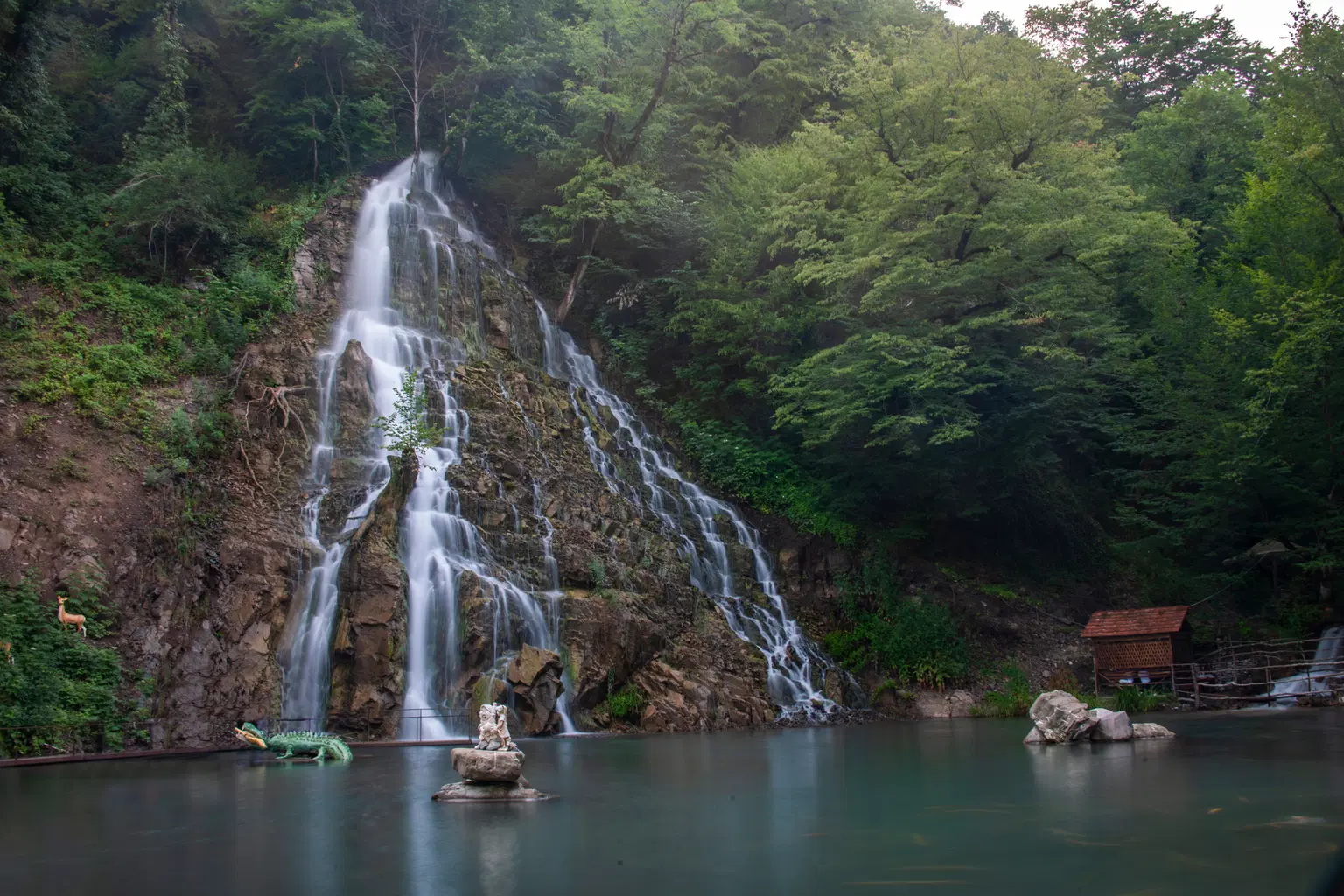 Afurdja Waterfall in Azerbaijan cascading down a rocky cliff surrounded by greenery.
