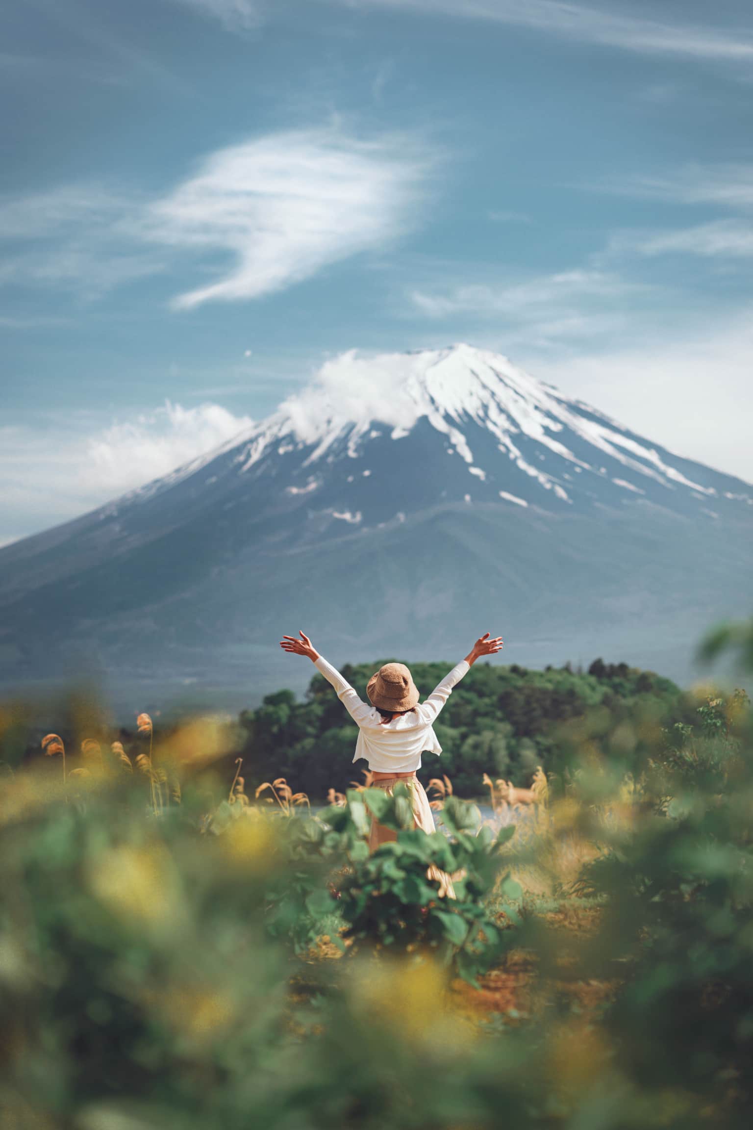 Woman with arms raised in front of Mount Fuji.